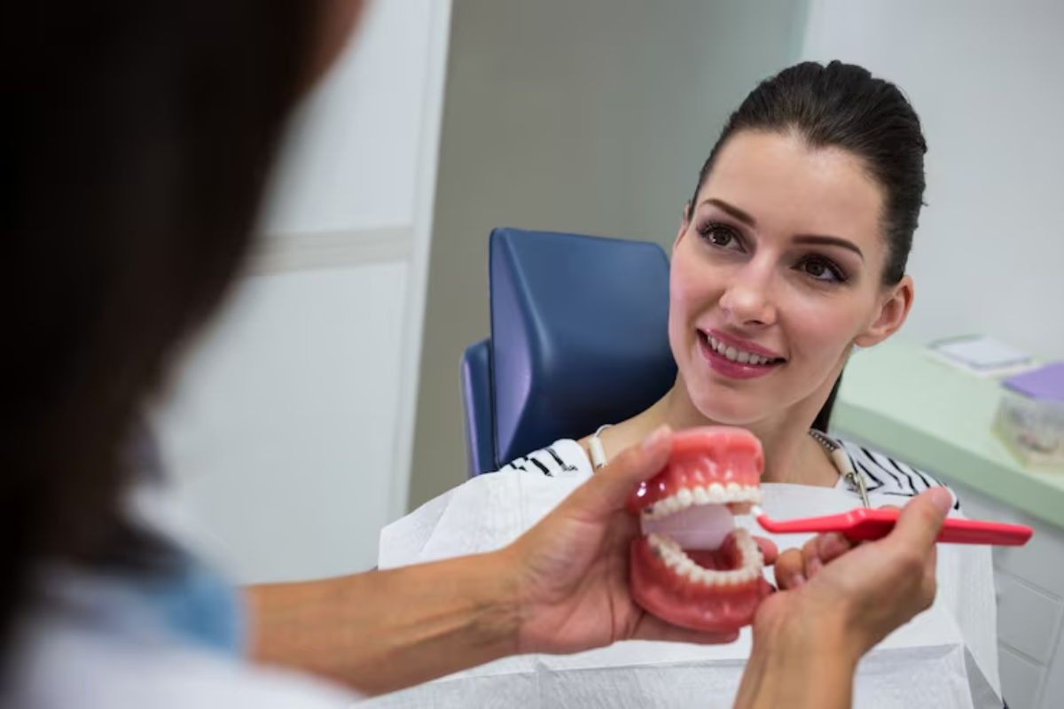 dental professional explaining how dental bridges work using a model of teeth and gums.