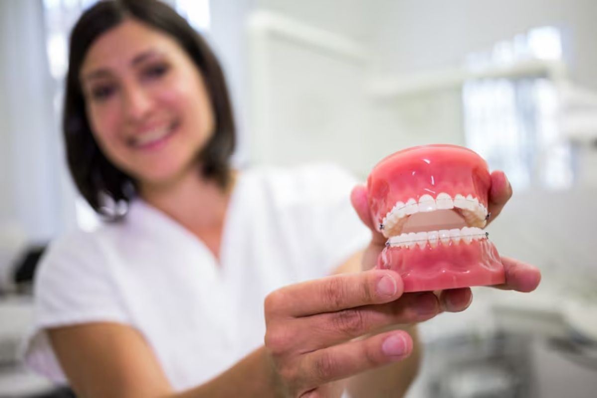 dentist holding a set of dentures while explaining how they replace missing teeth.