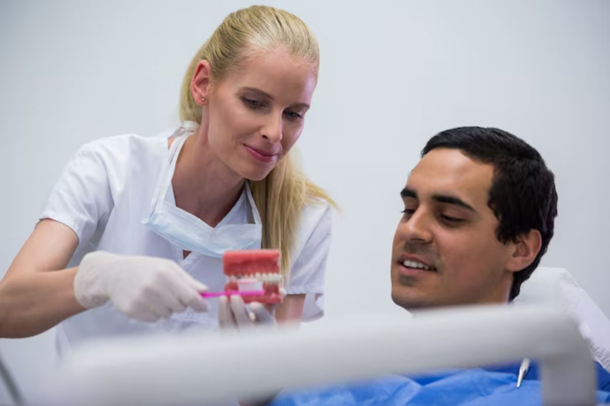 dentist explaining tooth care to a patient using a dental model.